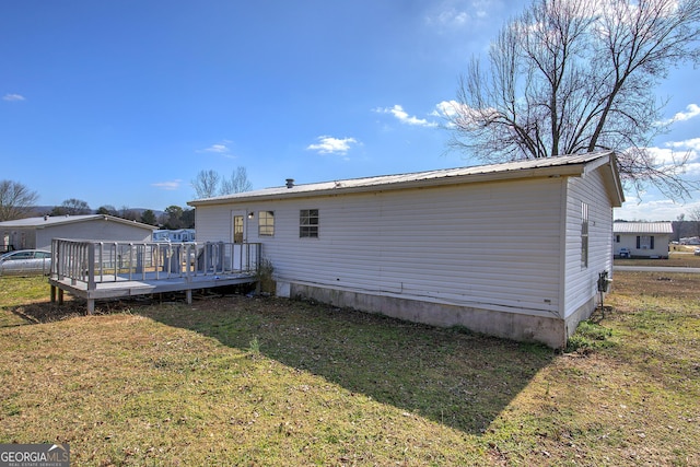 rear view of house with a deck and a lawn