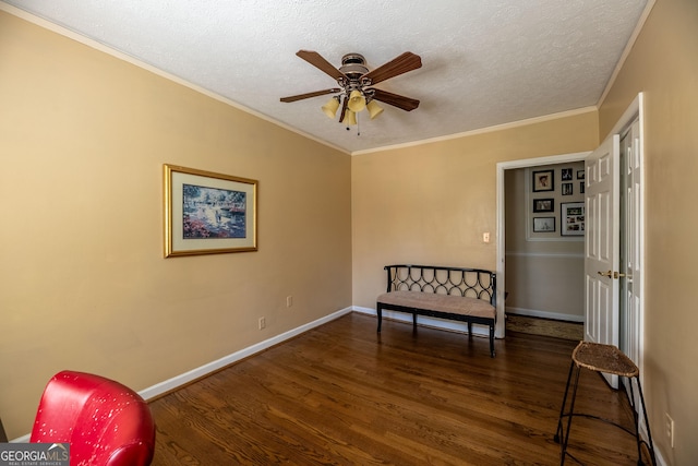 living area with ornamental molding, dark hardwood / wood-style floors, ceiling fan, and a textured ceiling