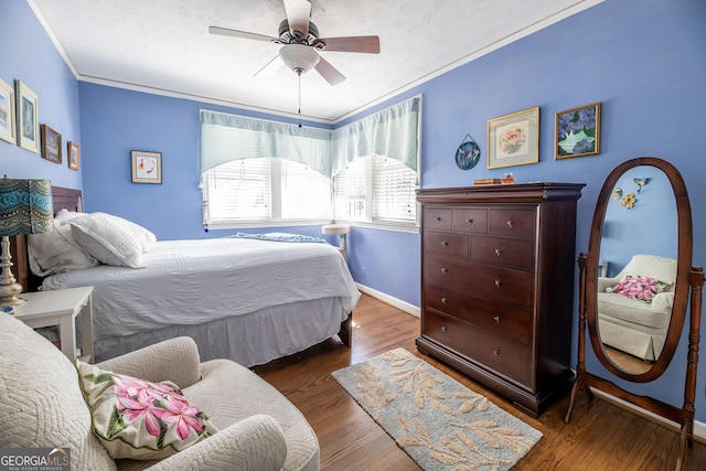 bedroom with ceiling fan, ornamental molding, dark hardwood / wood-style floors, and a textured ceiling