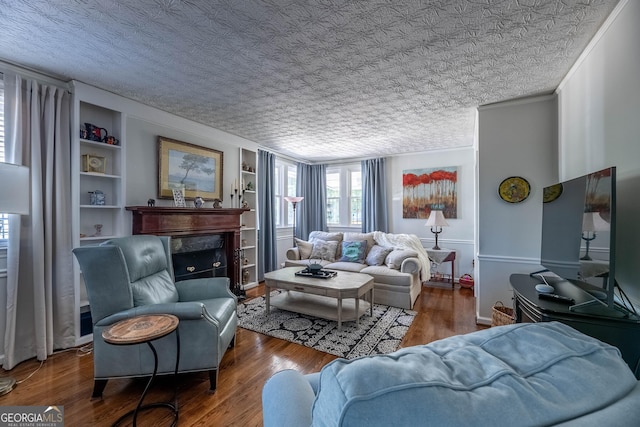 living room featuring hardwood / wood-style flooring, built in features, a high end fireplace, ornamental molding, and a textured ceiling