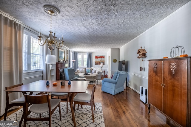 dining space featuring ornamental molding, a chandelier, hardwood / wood-style floors, and a textured ceiling