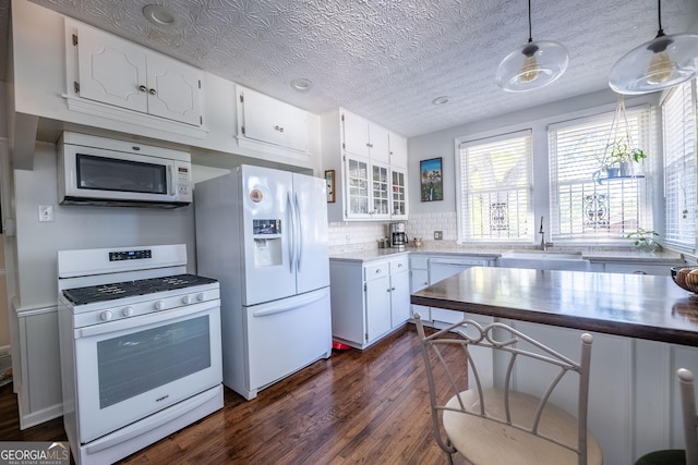 kitchen featuring decorative light fixtures, sink, white cabinets, dark wood-type flooring, and white appliances