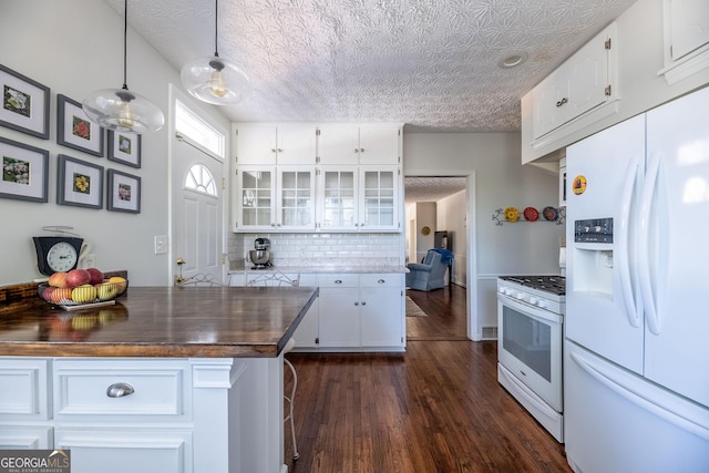 kitchen with white cabinets, dark hardwood / wood-style flooring, wooden counters, hanging light fixtures, and white appliances