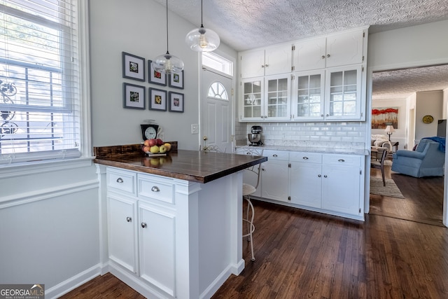 kitchen with dark hardwood / wood-style flooring, hanging light fixtures, a healthy amount of sunlight, and white cabinets