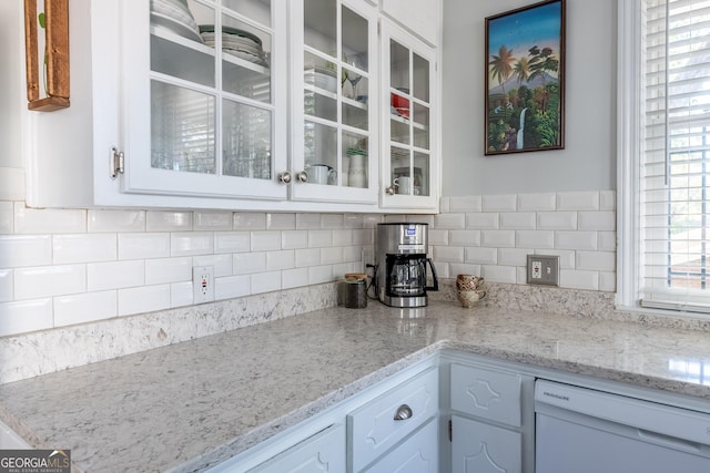 kitchen featuring white cabinetry, dishwasher, light stone counters, and decorative backsplash