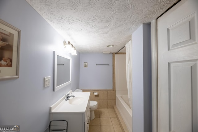 full bathroom featuring tile walls, tile patterned flooring, vanity, toilet, and a textured ceiling