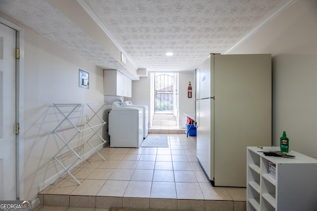 laundry area featuring washing machine and dryer, crown molding, light tile patterned flooring, and a textured ceiling