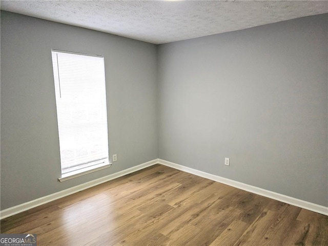 spare room featuring hardwood / wood-style floors and a textured ceiling