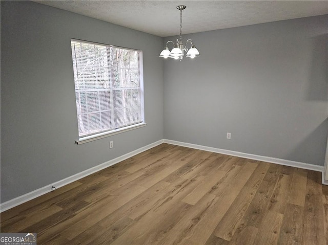 spare room featuring hardwood / wood-style floors, a textured ceiling, and a notable chandelier