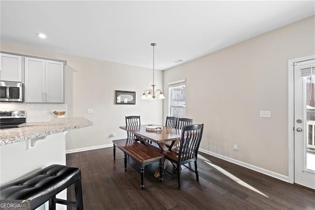 dining area with dark hardwood / wood-style flooring and a notable chandelier