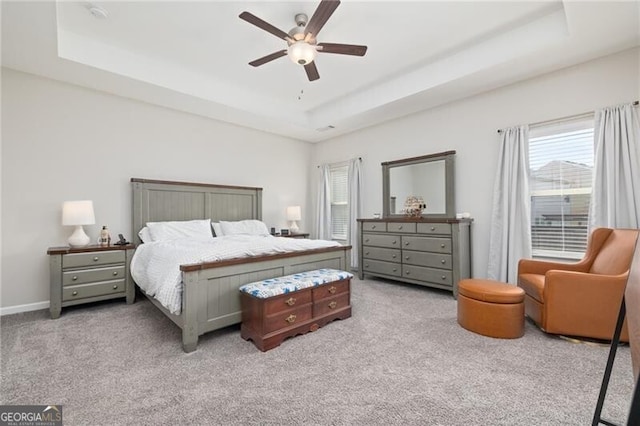 bedroom featuring ceiling fan, light colored carpet, and a raised ceiling