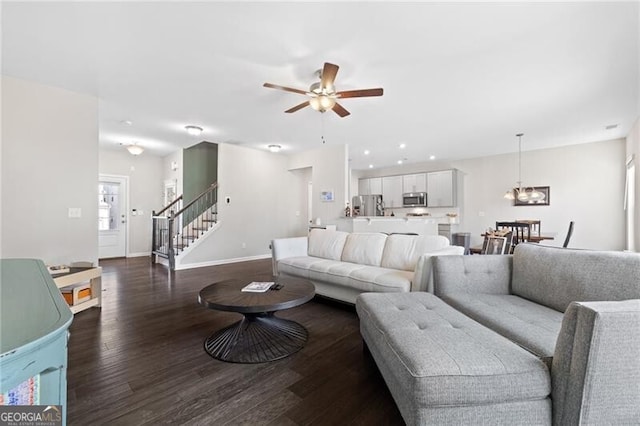 living room featuring dark wood-type flooring and ceiling fan with notable chandelier