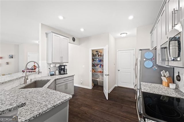 kitchen with dark wood-type flooring, sink, appliances with stainless steel finishes, light stone countertops, and decorative backsplash