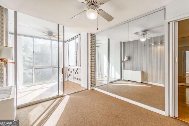 empty room with a wealth of natural light, carpet floors, and ceiling fan