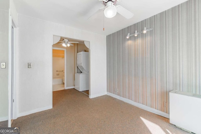 carpeted spare room featuring stacked washer and dryer and ceiling fan