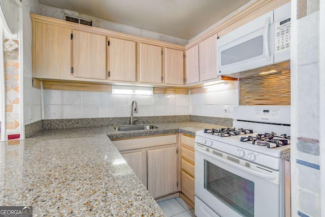 kitchen featuring sink, decorative backsplash, light stone countertops, light brown cabinets, and white appliances