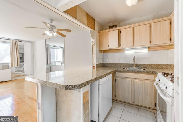 kitchen featuring sink, white appliances, backsplash, light stone counters, and kitchen peninsula