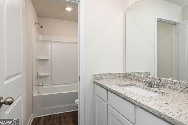 full bathroom with hardwood / wood-style flooring, vanity, shower / washtub combination, and toilet