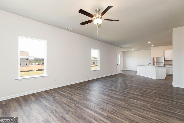 unfurnished living room featuring ceiling fan, sink, and dark hardwood / wood-style flooring