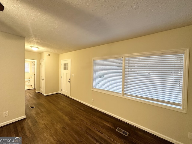 spare room featuring dark hardwood / wood-style floors and a textured ceiling