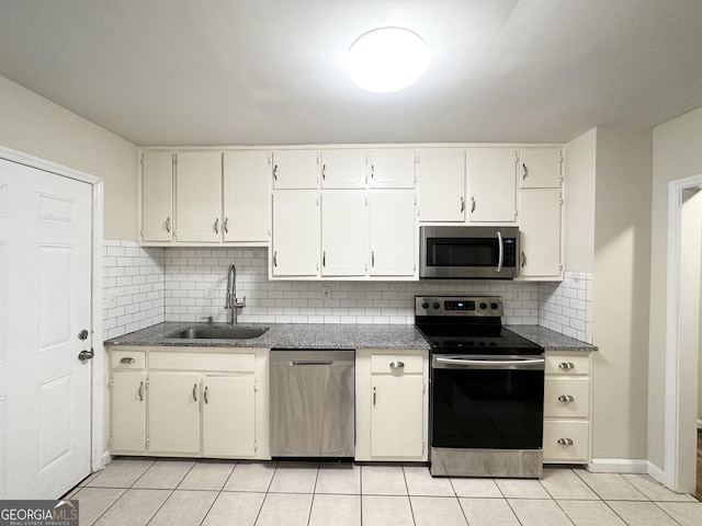 kitchen with sink, light tile patterned floors, backsplash, stainless steel appliances, and white cabinets