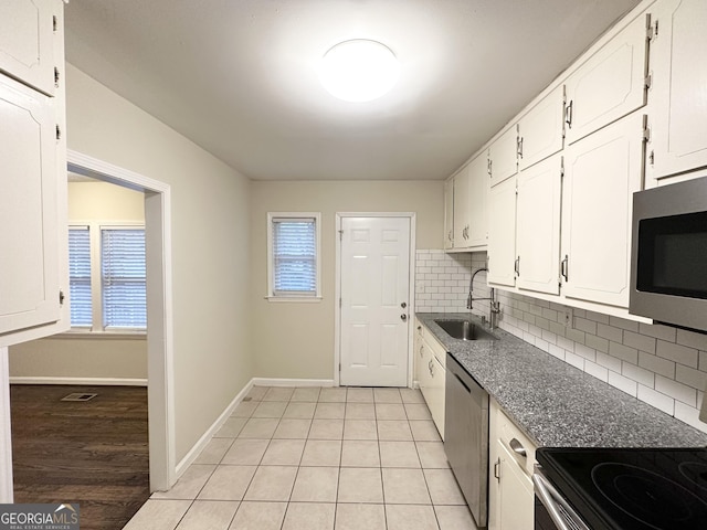 kitchen with sink, tasteful backsplash, light tile patterned floors, appliances with stainless steel finishes, and white cabinets