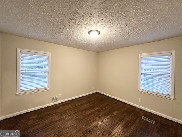 spare room with dark hardwood / wood-style floors and a textured ceiling