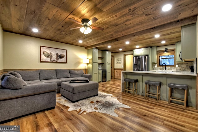 living room featuring sink, light hardwood / wood-style flooring, wooden ceiling, and ceiling fan