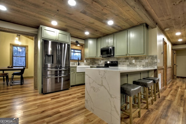 kitchen with appliances with stainless steel finishes, tasteful backsplash, wood ceiling, green cabinetry, and light hardwood / wood-style flooring