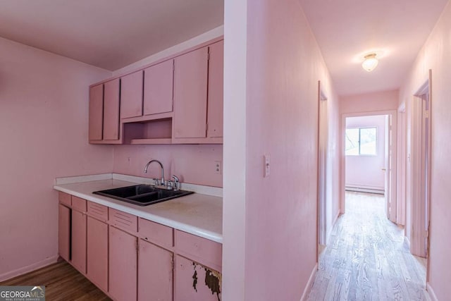 kitchen with a baseboard radiator, sink, and light hardwood / wood-style flooring