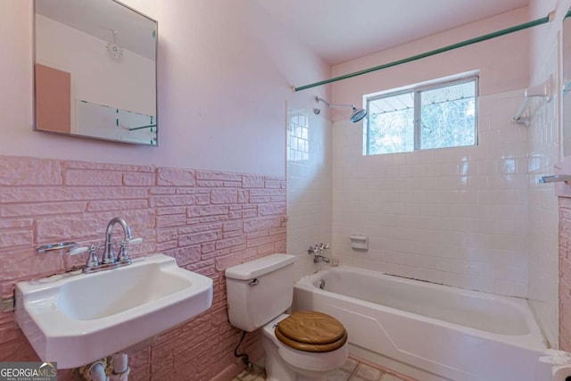 full bathroom featuring tiled shower / bath combo, sink, tile walls, and toilet