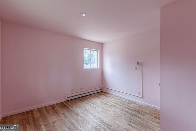 empty room featuring light wood-type flooring and baseboard heating