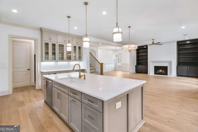 kitchen with pendant lighting, dishwasher, an island with sink, sink, and gray cabinetry