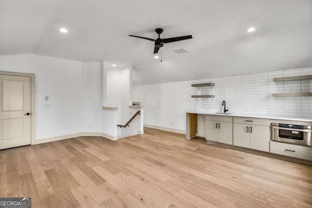 kitchen featuring tasteful backsplash, vaulted ceiling, sink, and stainless steel oven