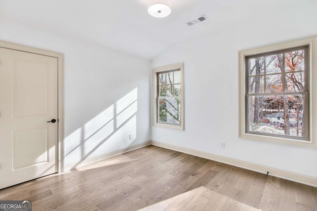 unfurnished room with lofted ceiling and light wood-type flooring