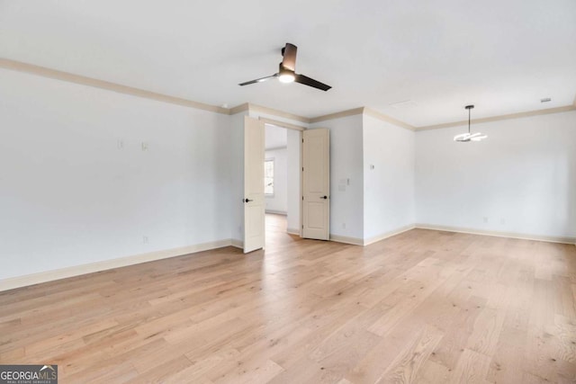 empty room with crown molding, ceiling fan with notable chandelier, and light wood-type flooring