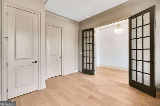 interior space featuring french doors, a chandelier, and light wood-type flooring