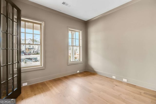 spare room featuring a wealth of natural light and light hardwood / wood-style floors