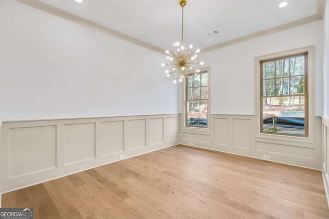 unfurnished dining area with a notable chandelier, light wood-type flooring, and a wealth of natural light