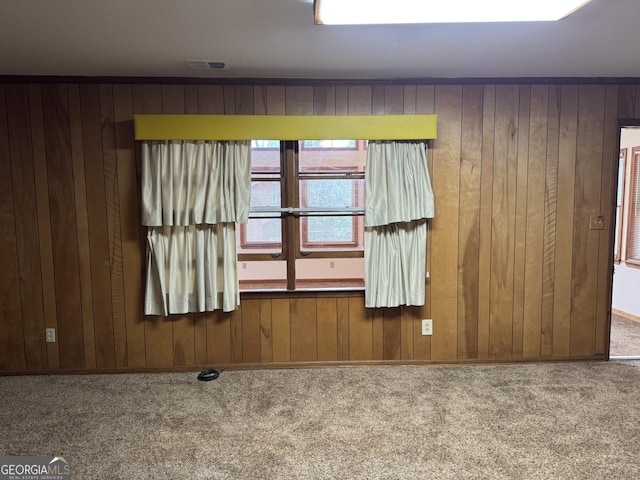 carpeted spare room featuring wooden walls