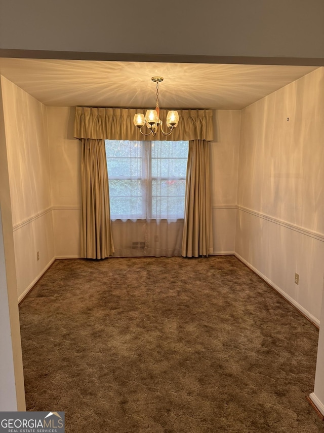 unfurnished room with dark carpet and a chandelier