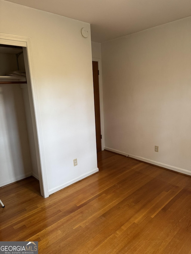 unfurnished bedroom with wood-type flooring and a closet