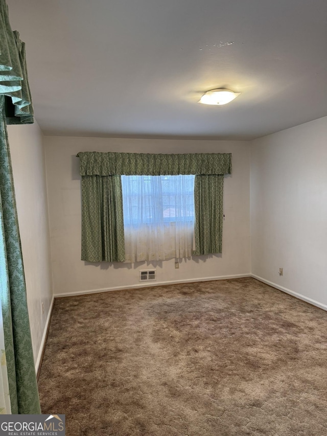 unfurnished room with dark colored carpet