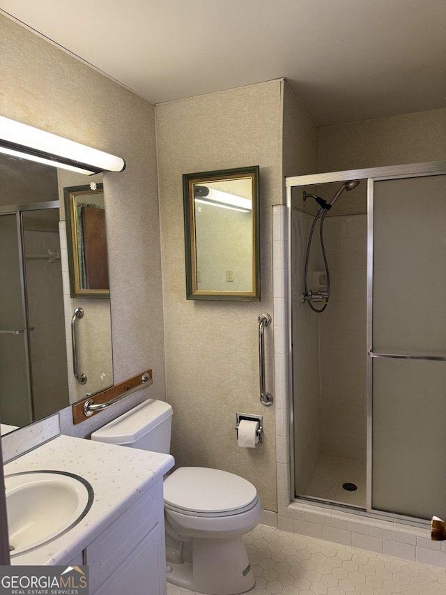 bathroom with vanity, tile patterned flooring, a shower with shower door, and toilet