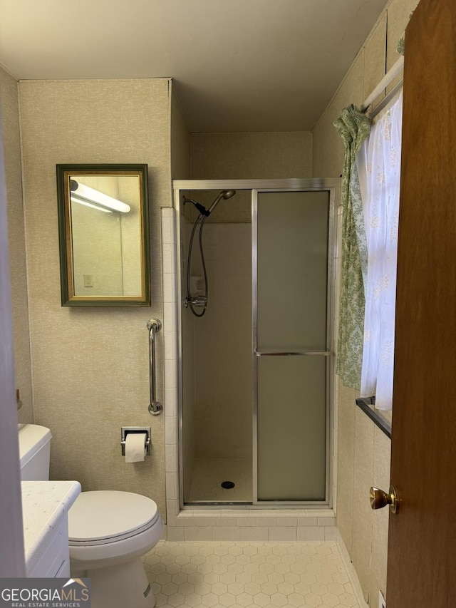 bathroom featuring a shower with door, vanity, tile patterned flooring, and toilet