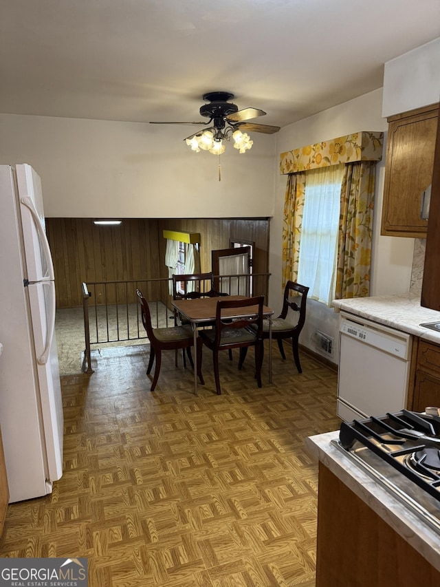 kitchen with light parquet floors, ceiling fan, wooden walls, and white appliances