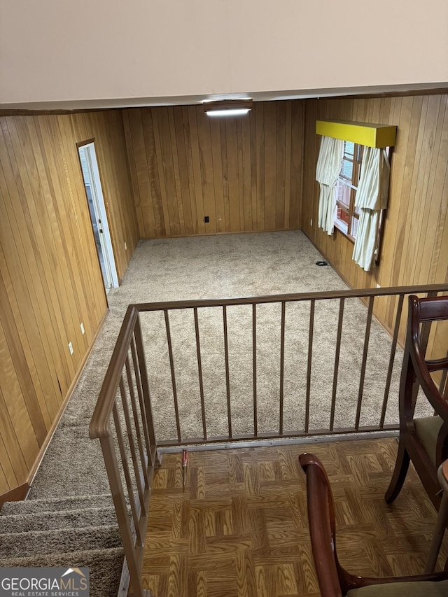 stairway with carpet flooring and wood walls