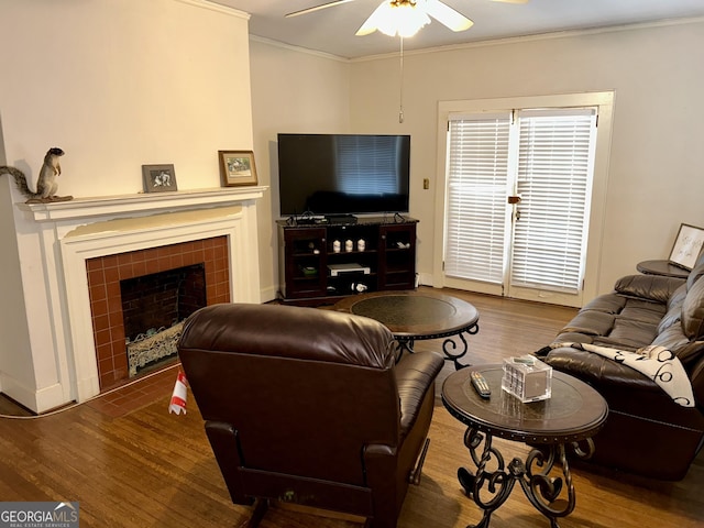 living room with ceiling fan, ornamental molding, hardwood / wood-style floors, and a tile fireplace