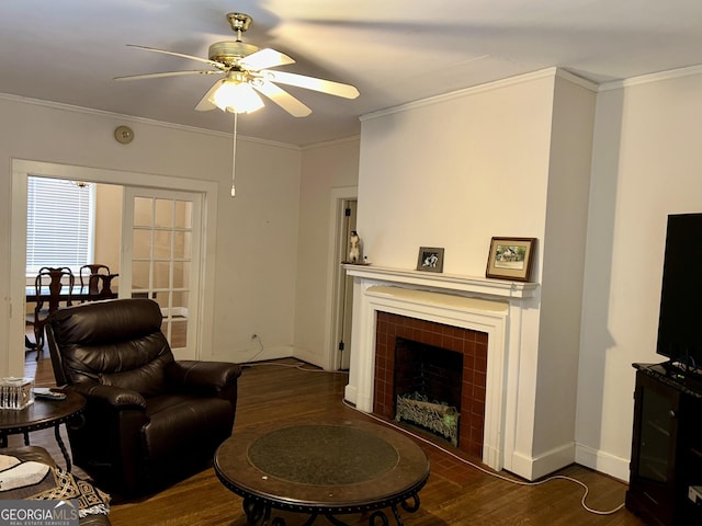 living room with dark hardwood / wood-style flooring, crown molding, ceiling fan, and a tiled fireplace