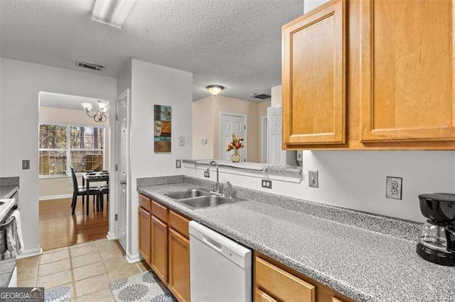 kitchen featuring dishwasher, sink, a chandelier, light tile patterned floors, and a textured ceiling